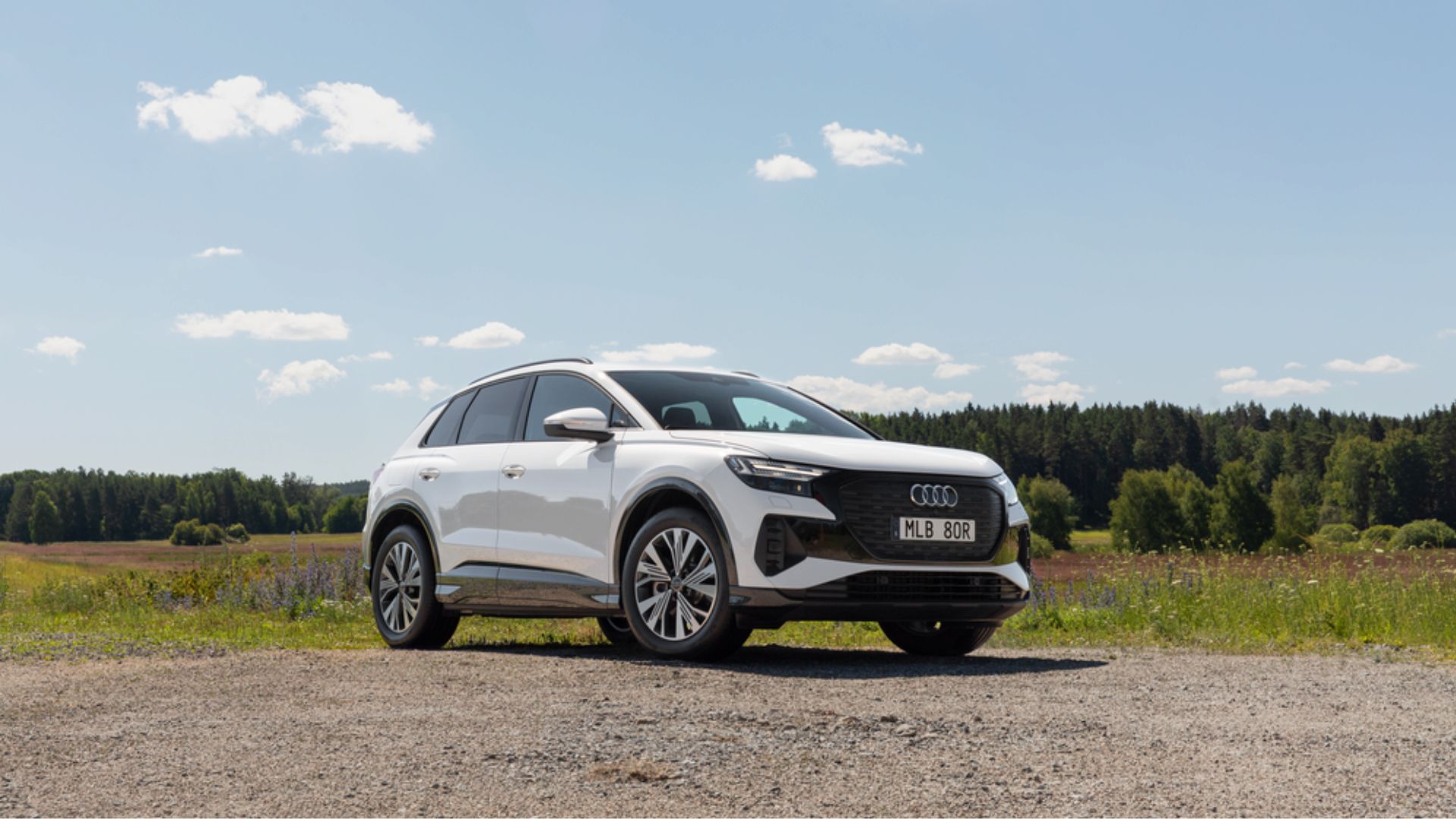 Vit Audi Q4 proline parkerad på grusplan, men lite grönska i bakgrunden.